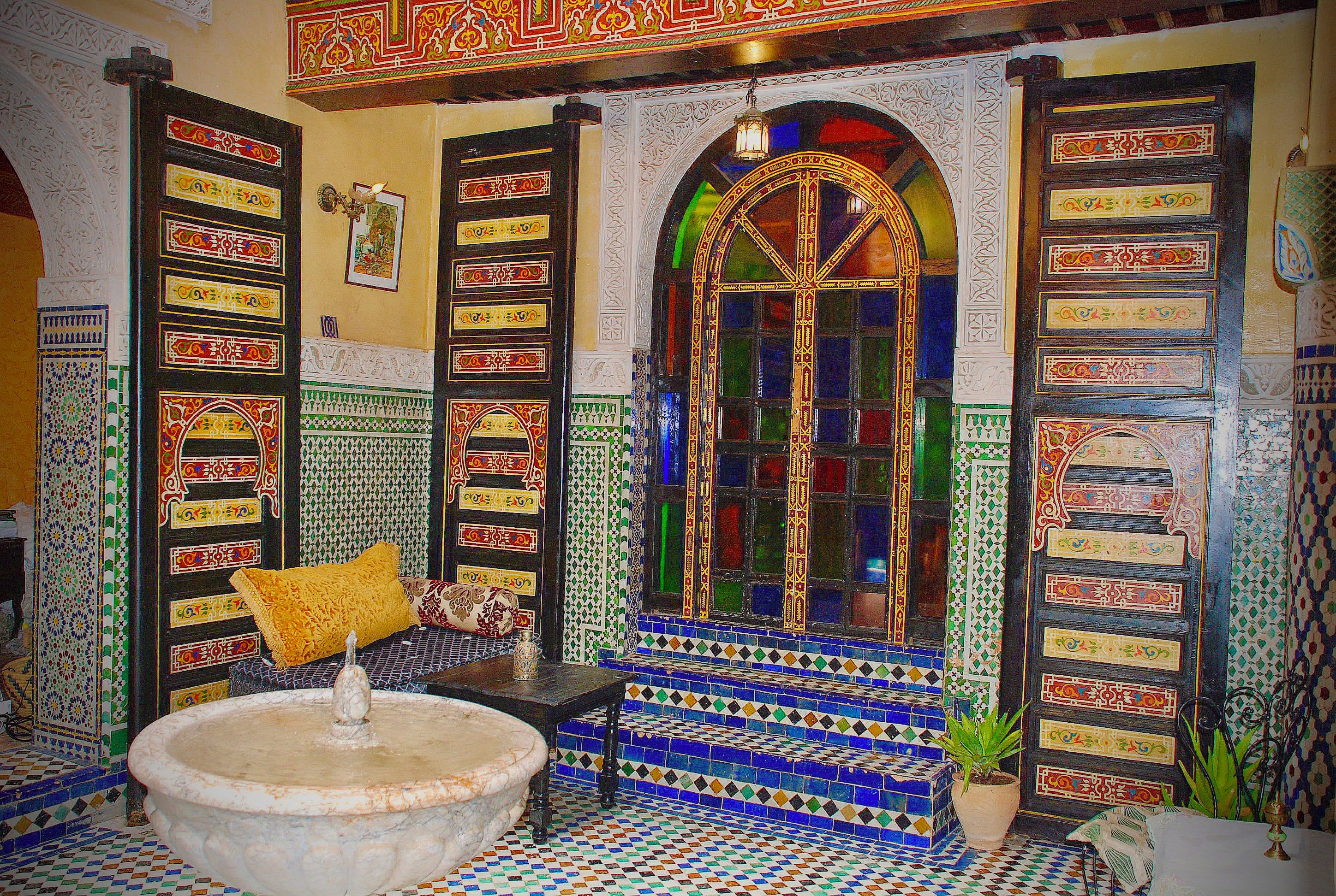 Una habitación con una fuente, paredes con diseños y un amplio ventanal de arco.