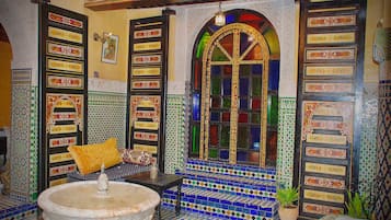 Una habitación con una fuente, paredes con diseños y un amplio ventanal de arco.