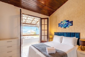 A bedroom with a bed, a nightstand, a window, and a view of the outdoors.