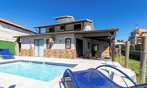 A two-story house with a swimming pool, a covered patio, and a fenced backyard.