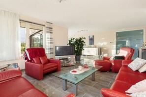 A modern living room with red leather sofas, a glass coffee table, and a flat-screen TV. - Boulevard de Wielingen 30 (Cadzand)