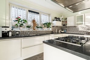 Une cuisine moderne avec des meubles blancs, un plan de travail noir et une cuisinière à gaz.