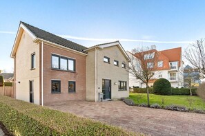Ein zweistöckiges Wohnhaus mit Backsteinfassade, einem gepflasterten Auffahrt und einem gepflegten Rasen.