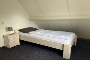 A single bed with a headboard, a bedside table with drawers, and a lamp. - Holiday apartment with 3 bedrooms (OUDDORP)