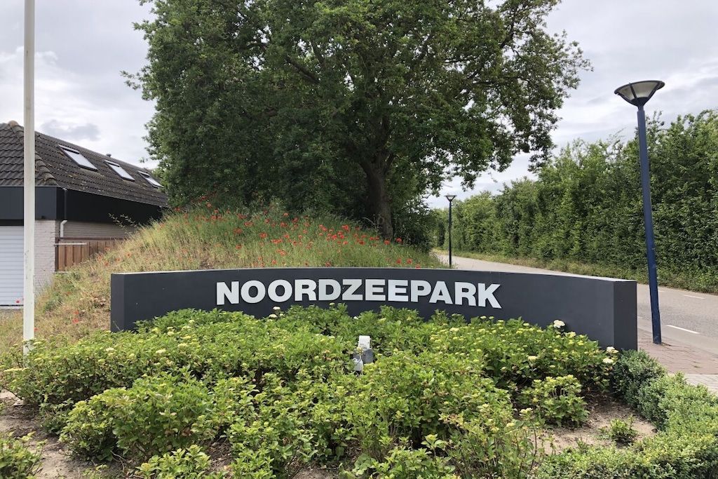 Señal de NOORDZEE PARK con un jardín paisajístico al frente.