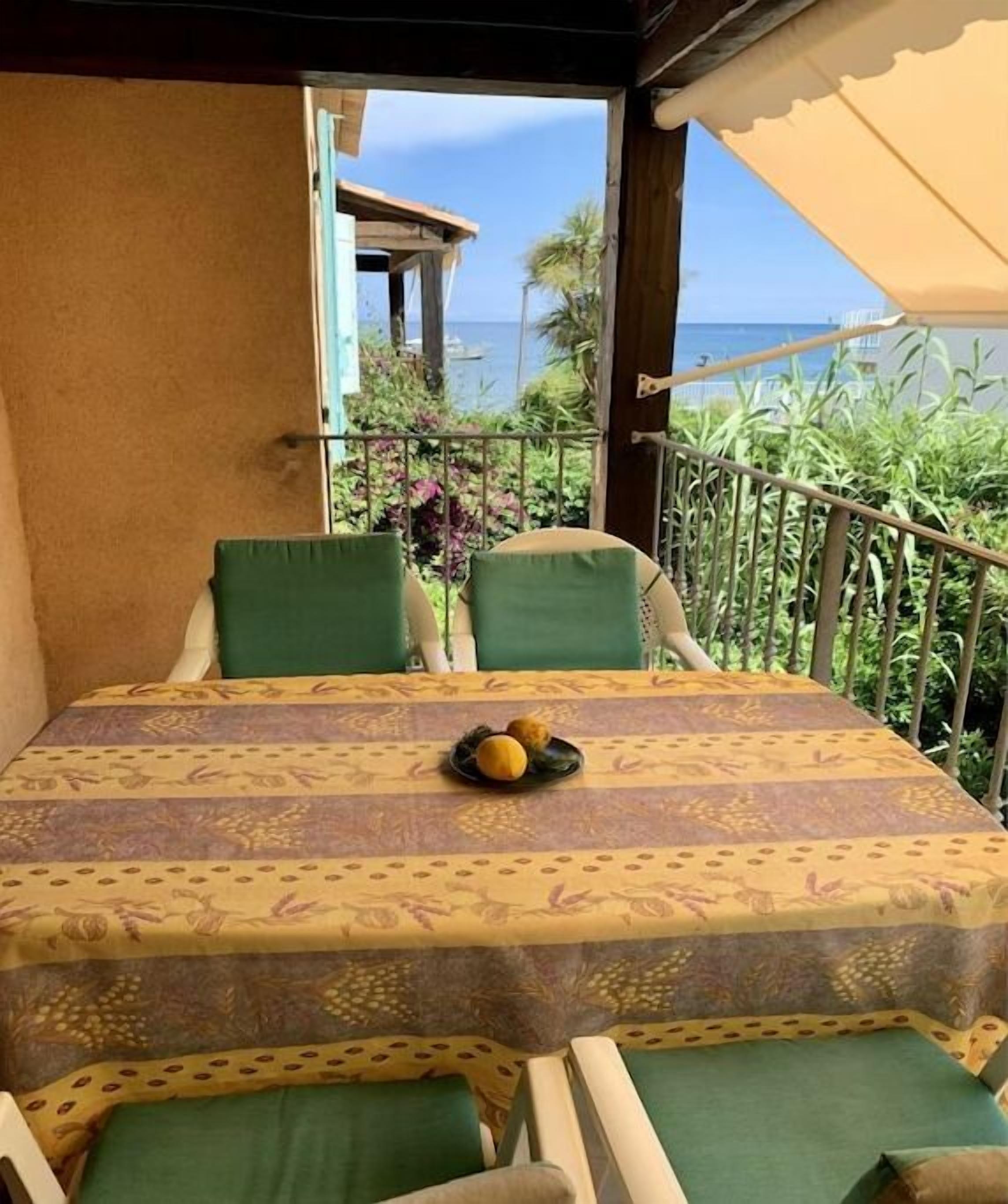 A balcony with a table and chairs, a view of the sea, and a railing.