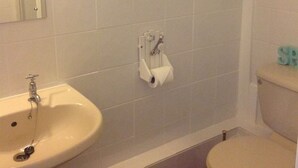 A bathroom with a sink, toilet, and a towel dispenser.