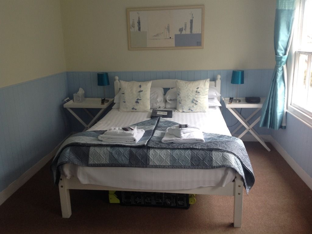 A neatly made bed with a blue and white patterned bedspread, two bedside tables with lamps, and a painting on the wall.