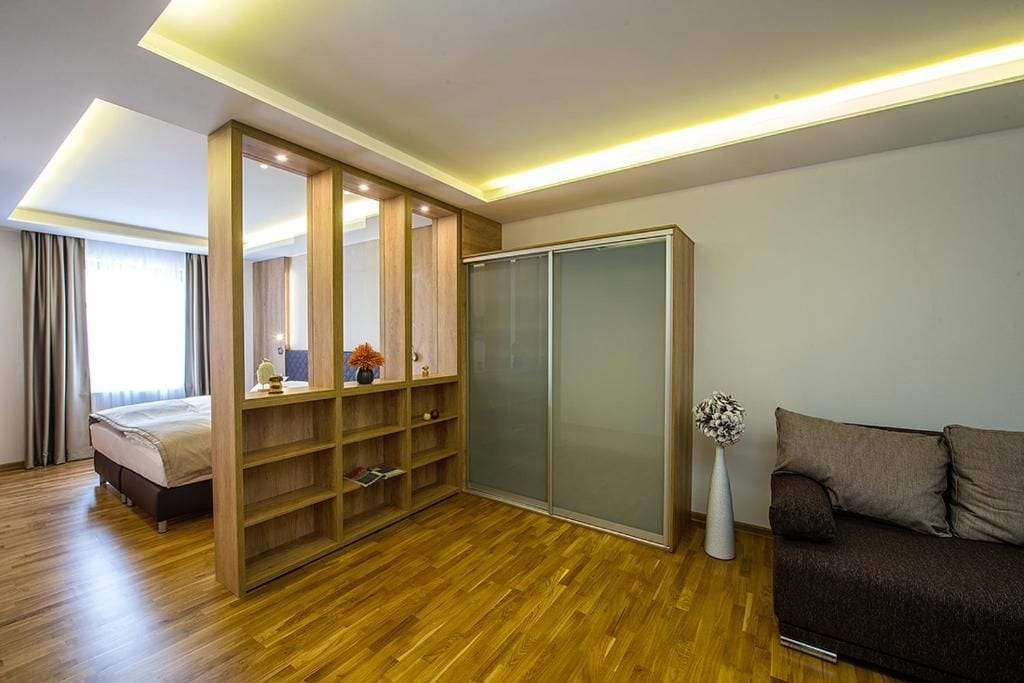 A modern bedroom with a wooden floor, a bed, a wardrobe, and a sofa.