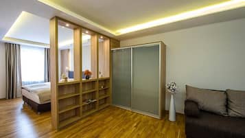 A modern bedroom with a wooden floor, a bed, a wardrobe, and a sofa.