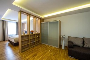 Un dormitorio moderno con suelo de madera, una cama, un armario y un sofá.