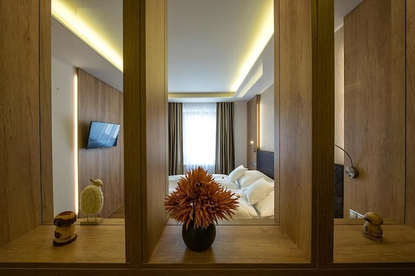 A hotel room with a bed, a television, and a vase of flowers.
