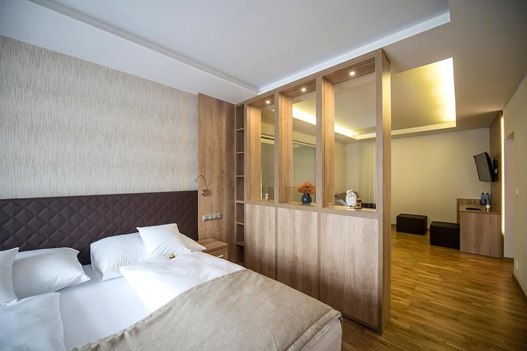 Una habitación de hotel con una cama, un armario de madera, un espejo, un escritorio y un televisor.