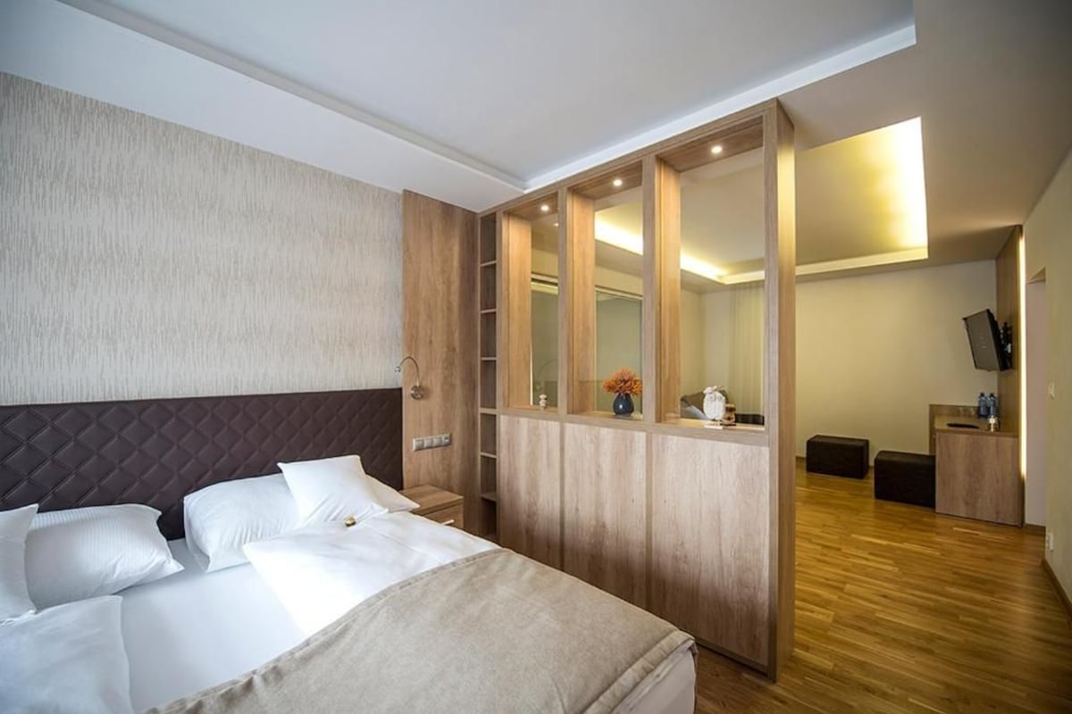 Habitació d'hotel amb un llit, un armari de fusta, un mirall, una taula de treball i una televisió.
