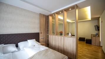 Una habitación de hotel con una cama, un armario de madera, un espejo, un escritorio y un televisor.