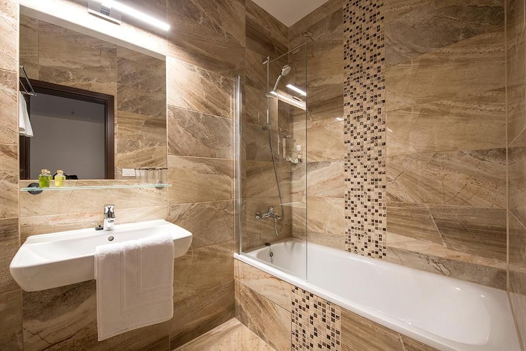 Een moderne badkamer met een douchecabine van glas, een witte wastafel en een ruim bad.