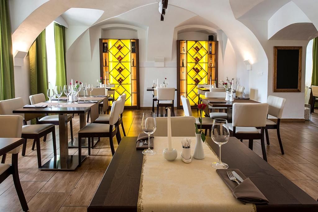 Restaurante com mesas preparadas para refeições, apresentando design moderno, piso de madeira e cadeiras brancas.