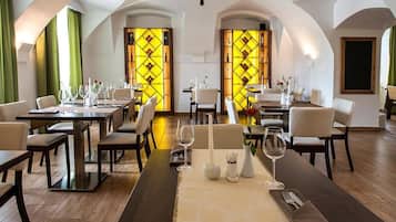 Restaurante com mesas preparadas para refeições, apresentando design moderno, piso de madeira e cadeiras brancas.
