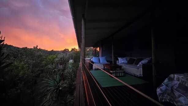 A balcony with a view of a sunset, a sofa, and a table. - Off-grid, luxury river-view  with private nature trails & hot tub Sedgefield (Sedgefield)