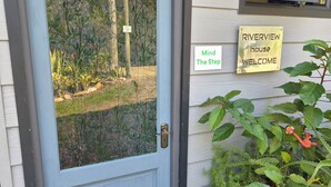 A blue door with a brass doorknob, a welcome sign, and a doormat with blue and white tiles. - Off-grid, luxury river-view  with private nature trails & hot tub Sedgefield (Sedgefield)