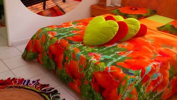 Un dormitorio con cama, mesita de noche, espejo y decoración en la pared.