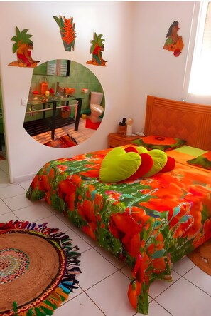 A bedroom with a bed, a nightstand, a mirror, and a wall decoration.