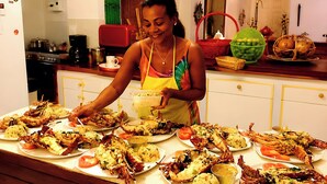 A person serving food on a table with various dishes, including seafood and rice.