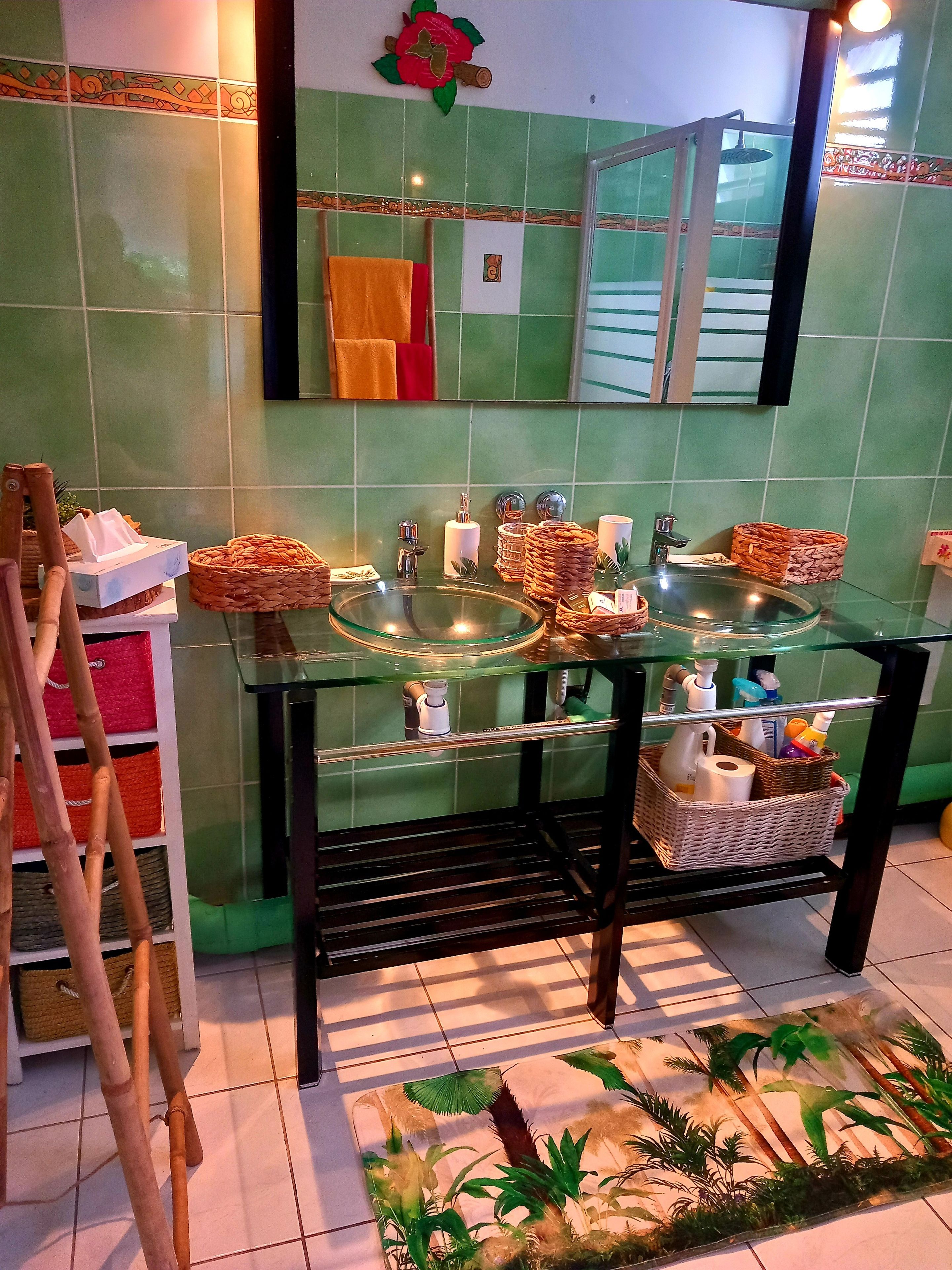 Un baño con lavamanos de vidrio, un espejo y cabina de ducha.