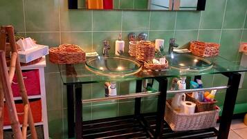 Un baño con lavamanos de vidrio, un espejo y cabina de ducha.