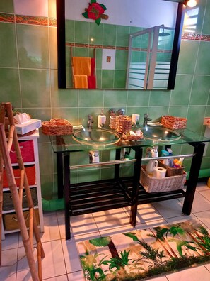A bathroom with a glass sink, a mirror, and a shower enclosure.