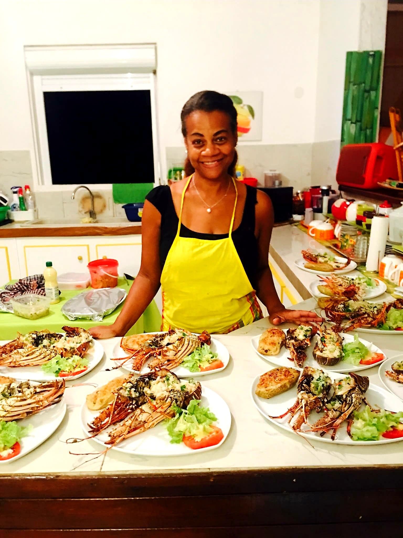 Une personne portant un tablier jaune se tient derrière une table sur laquelle sont disposés plusieurs plats de homard.