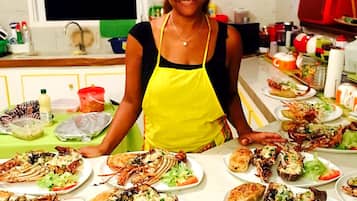 Une personne portant un tablier jaune se tient derrière une table sur laquelle sont disposés plusieurs plats de homard.