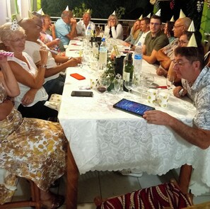 Un groupe de personnes est assis autour d’une table recouverte d’une nappe blanche. On y voit différents verres, des bouteilles et un téléphone intelligent.