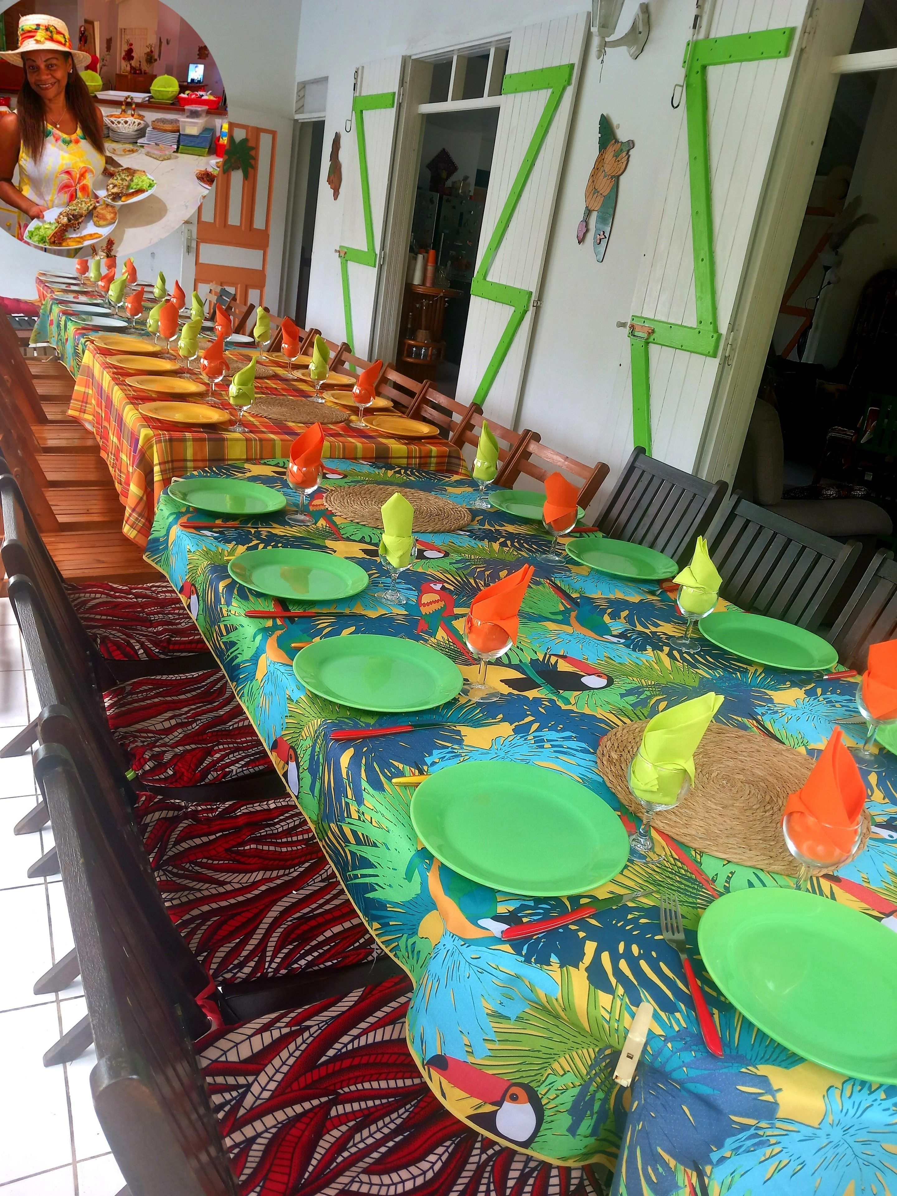 A long dining table with colorful tablecloths and green plates, set for a meal.