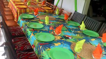 A long dining table with colorful tablecloths and green plates, set for a meal.