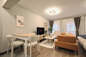 A modern living room with a dining area, a sofa, a TV, and a plant. - Modern 2br, Living Areas, 2 Baths, Kadıköy (Istanbul)