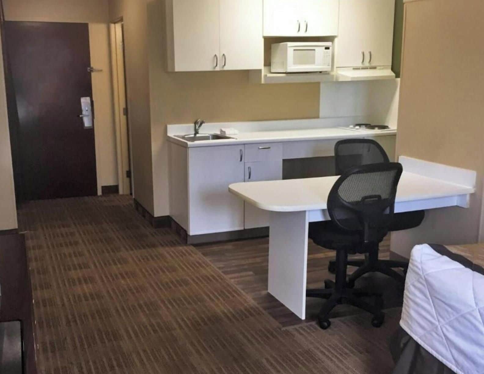 Habitació d'hotel amb petita cuina, escriptori i cadira.