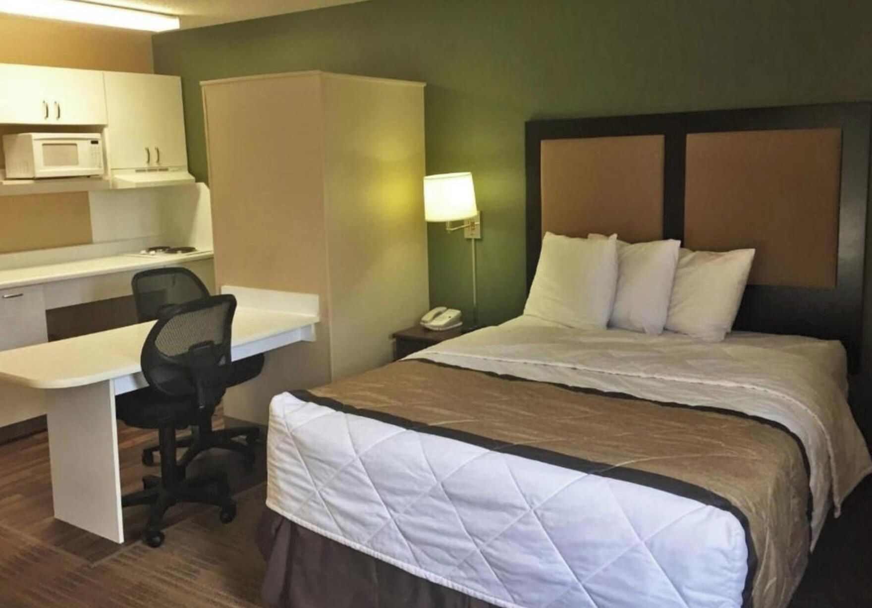 Ein Hotelzimmer mit Bett, Schreibtisch, Stuhl und einer Mikrowelle.