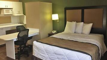 Ein Hotelzimmer mit Bett, Schreibtisch, Stuhl und einer Mikrowelle.