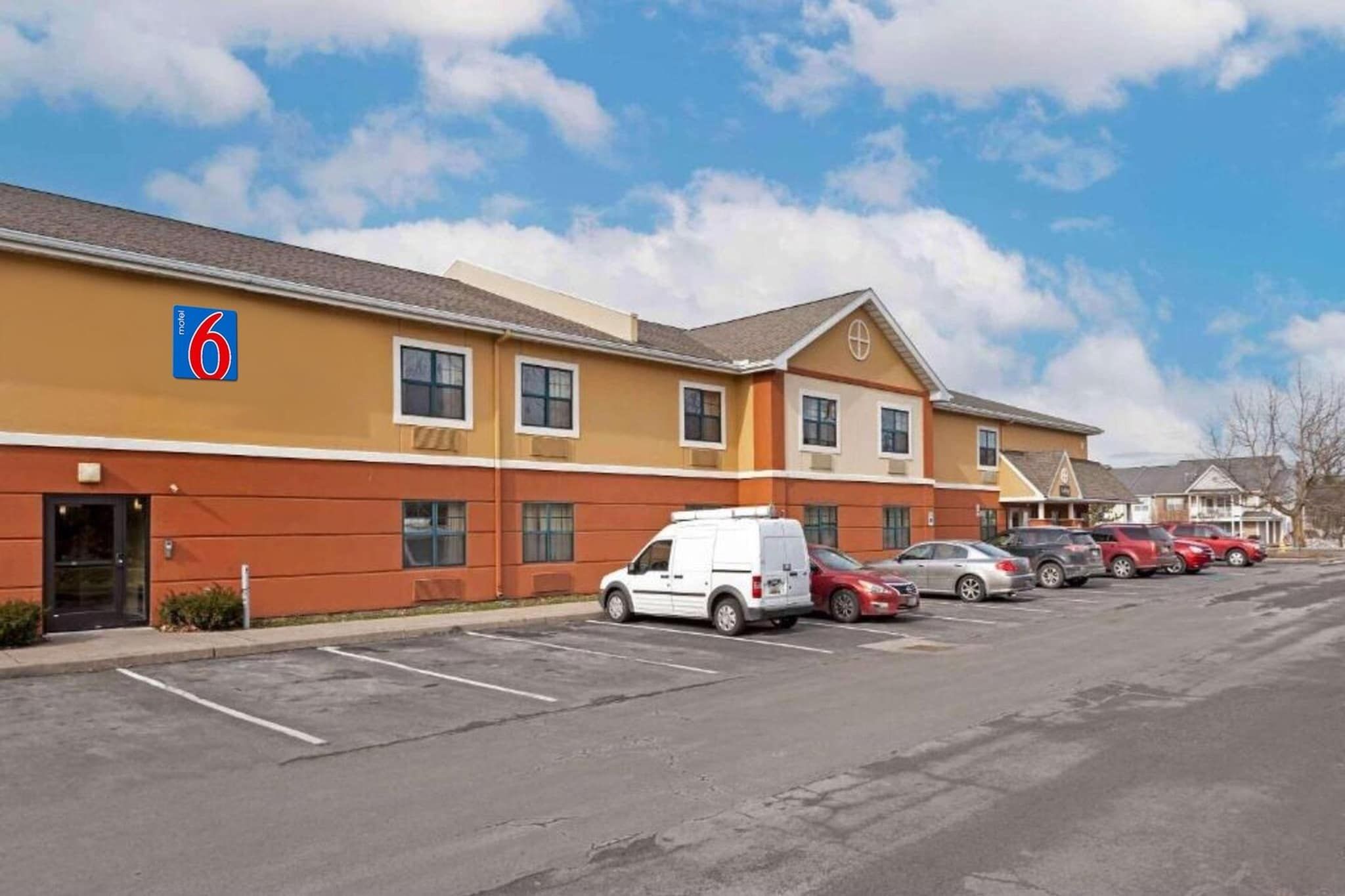 A motel with a parking lot and several parked cars.