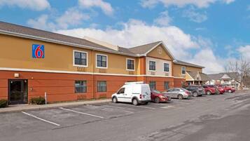 A motel with a parking lot and several parked cars.