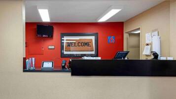A reception desk with a 'WELCOME' sign, a television, a phone, and a computer.