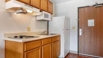 A kitchen with wooden cabinets, a microwave, a sink, and a refrigerator.