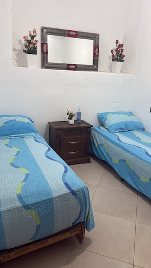 A bedroom with two beds, a dresser, a mirror, and a small shelf with flowers. - DAR LALLA KHADIJA (RABAT)