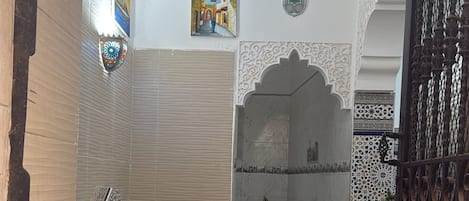 A hallway with a decorative ceiling, a door with a metal gate, and a potted plant.