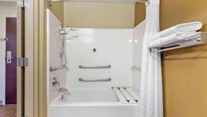 Een badkamer met een bad, een douche en een handdoekhouder.