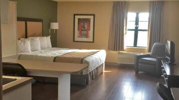 A hotel room with a bed, a desk, a chair, a television, and a window with curtains.