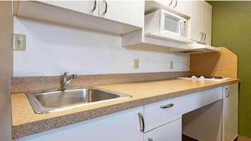 A kitchen with a double sink, white cabinets, a microwave, and a gas stove.