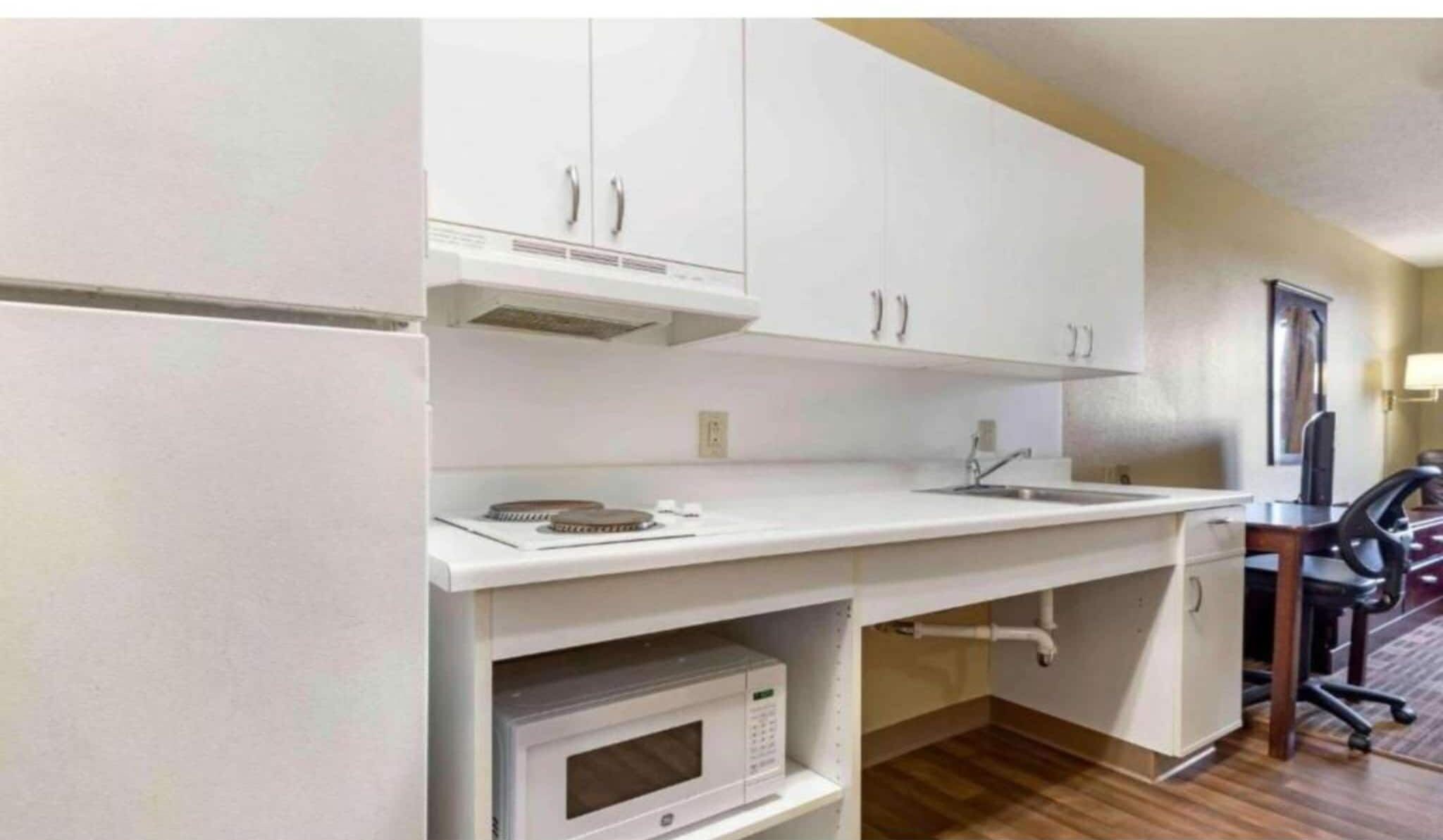 A compact kitchen with white cabinets, a microwave, and a sink.