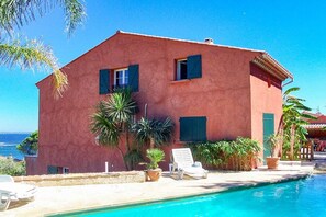 A two-story building with a pool, palm trees, and a clear view of the sea. - Villa in Carqueiranne with swimming pool (Carqueiranne)